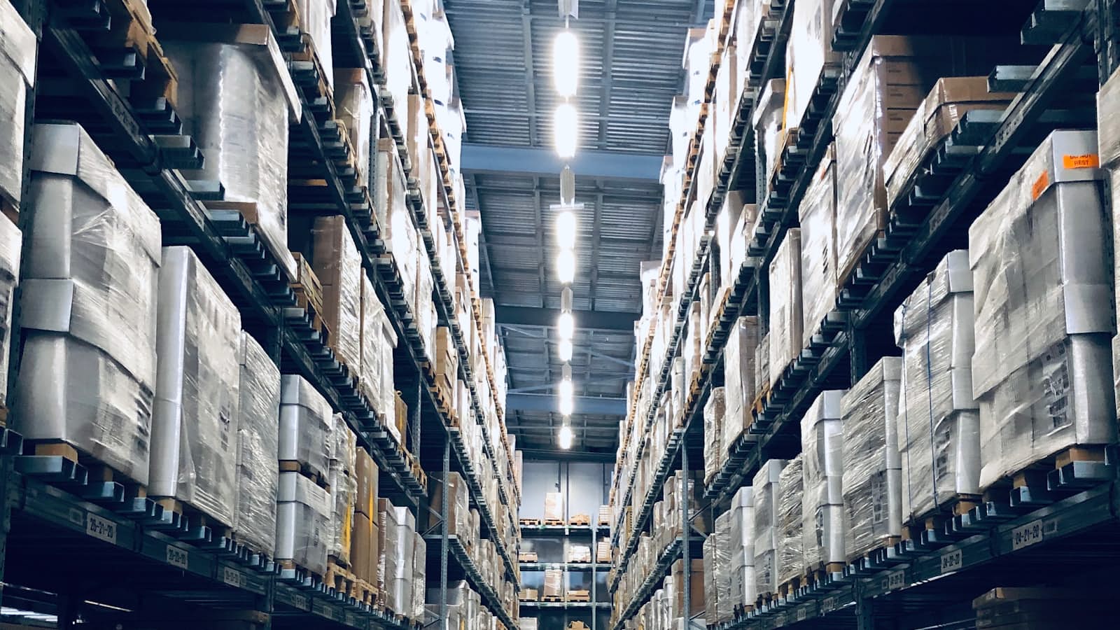 Wide aisle of a wholesale distribution warehouse stacked with palletised inventory